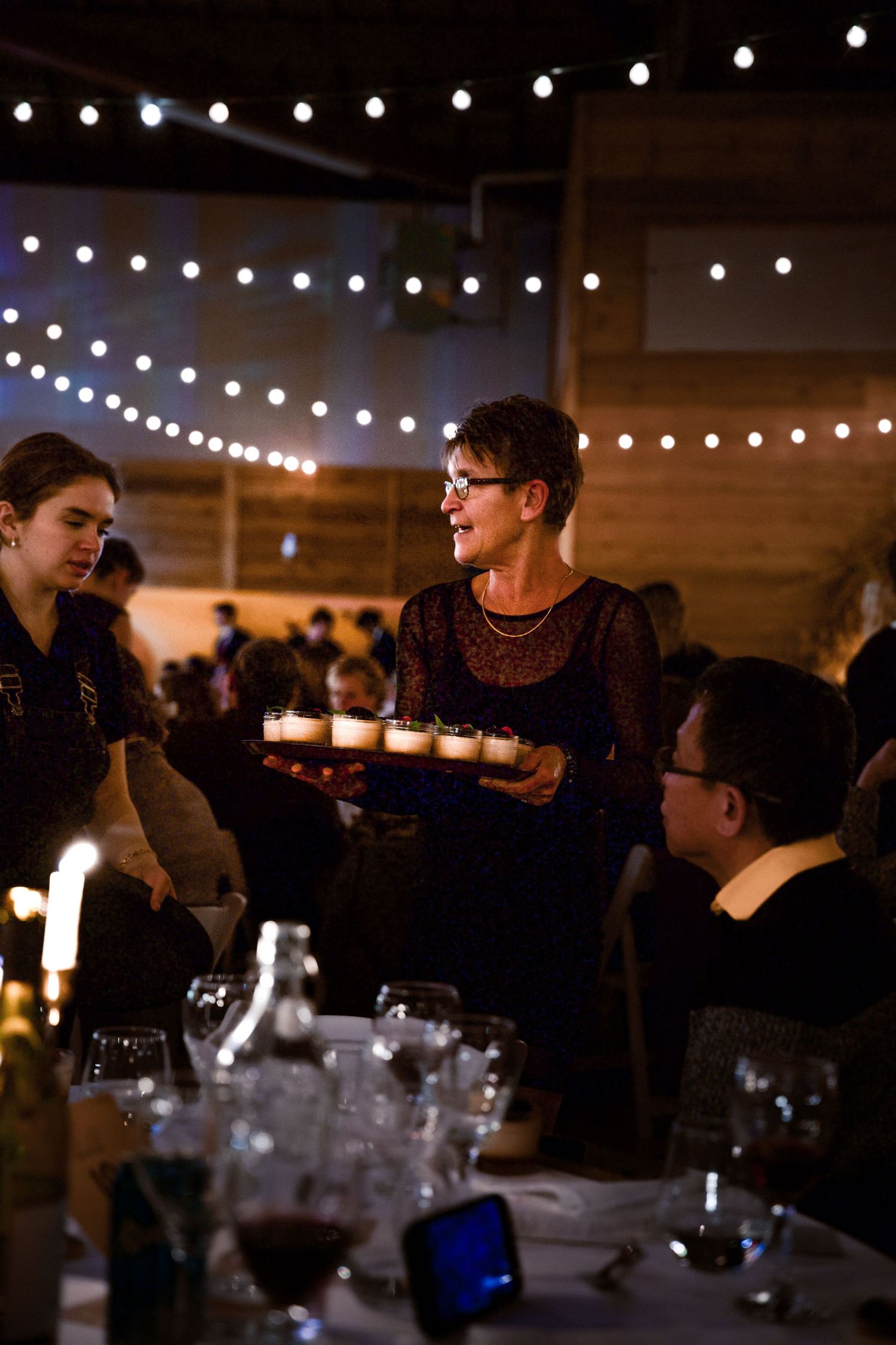 String lights illuminate a casual dining gathering in a rustic indoor space.