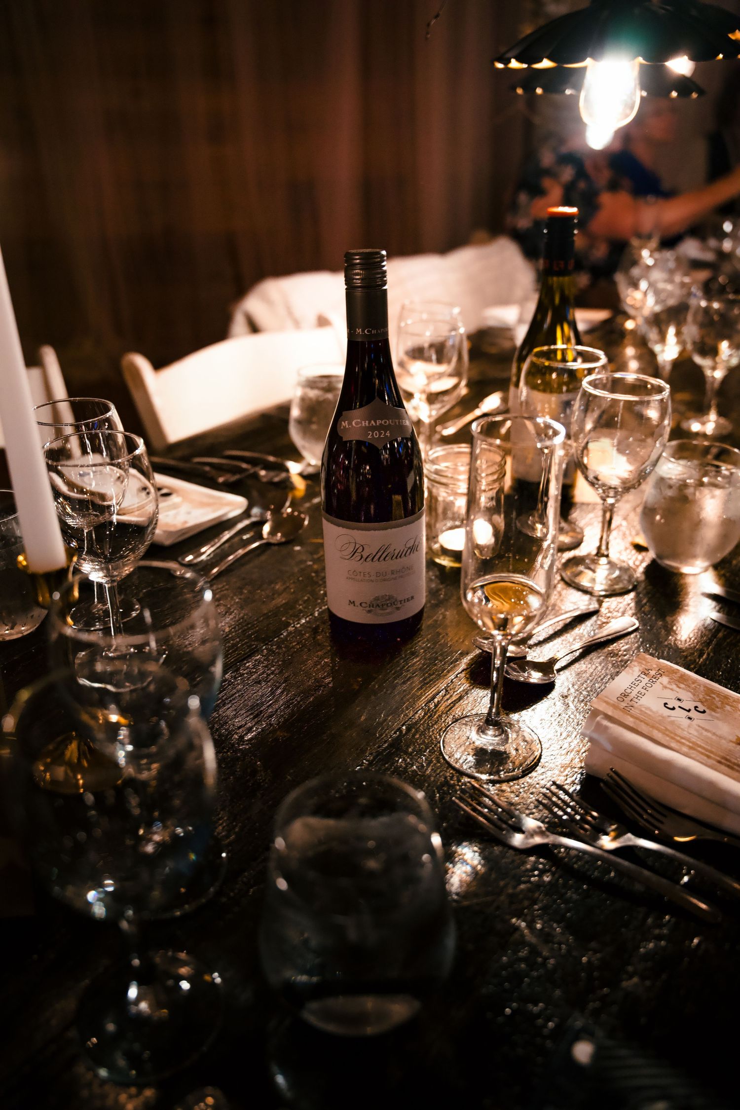 Elegant table setting with wine bottles and glasses illuminated by candlelight.