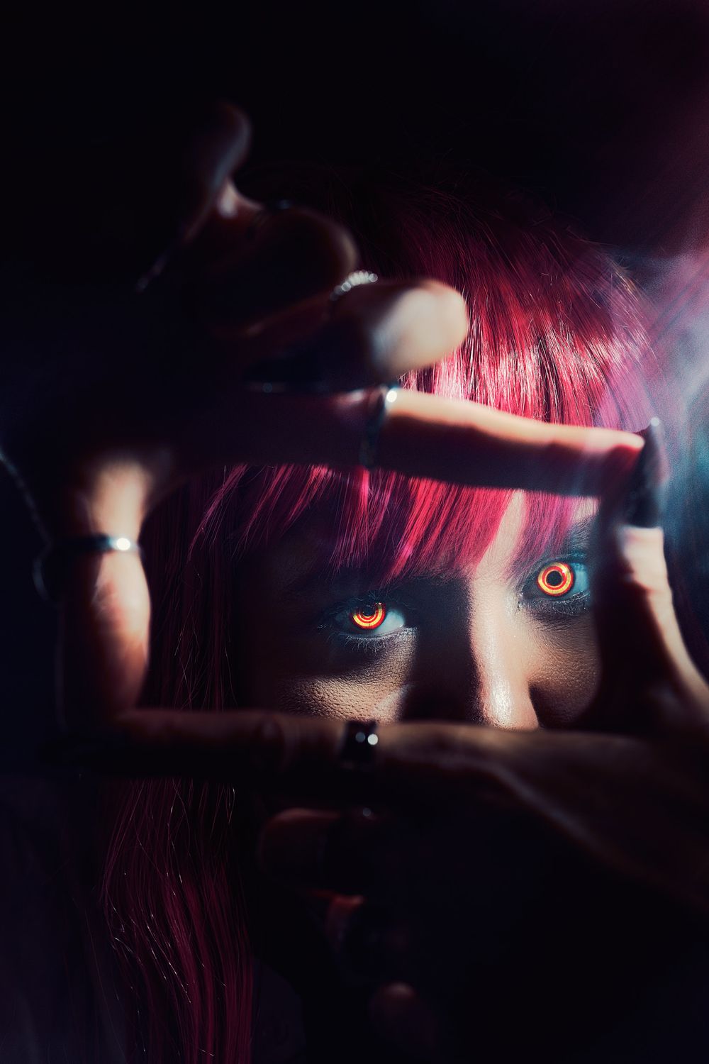 Close-up artistic portrait with pink hair and dramatic lighting showing a single eye in darkness.