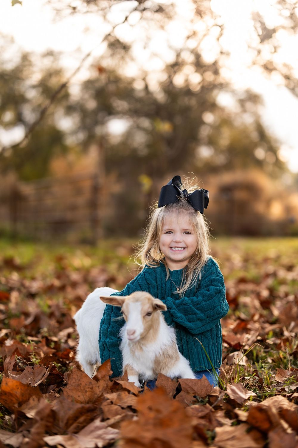 Joyful playtime with a white goat amid a carpet of brown autumn leaves.