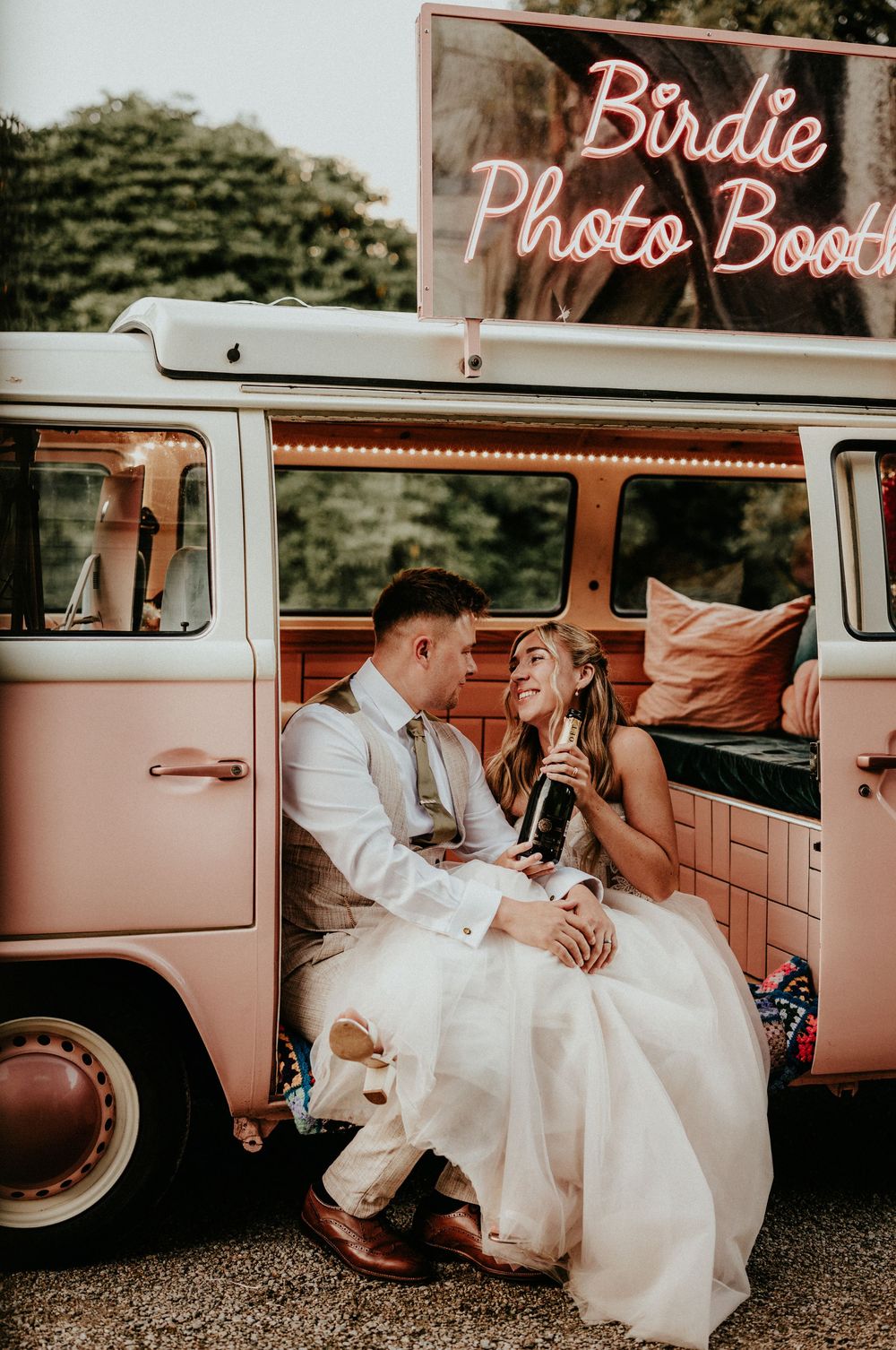A series of romantic wedding photos showing a couple posing in and around a vintage pink photo booth car. Cornwall wedding photographer