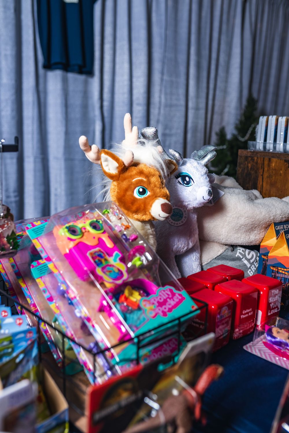 Colorful plush toys and books arranged on a shelf with soft lighting creating a cozy display.