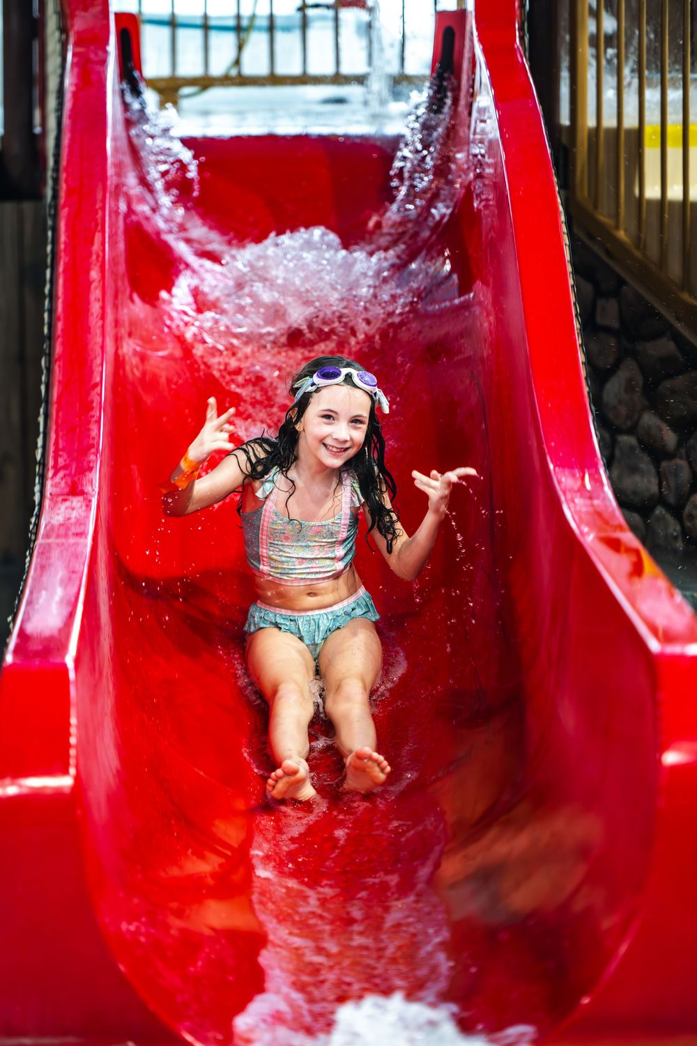 A sequence of photos shows a person joyfully sliding down a bright red water slide at a water park.