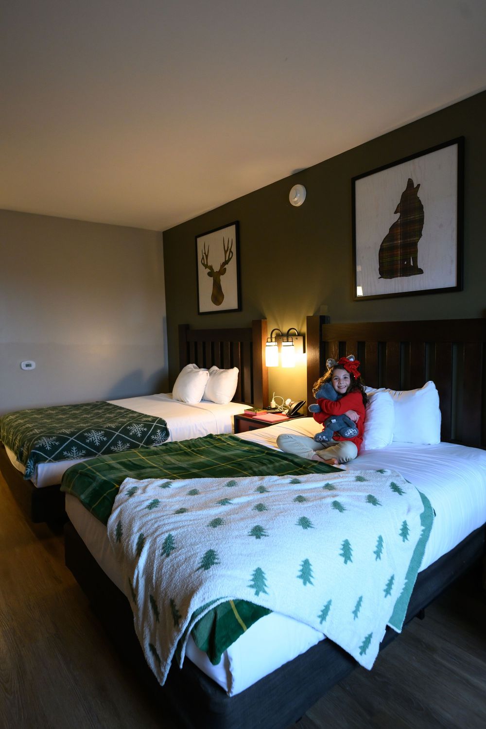 A GreatWolf Lodge Perryville, MD hotel room with dark walls features deer-themed decor and Christmas bedding in multiple views.