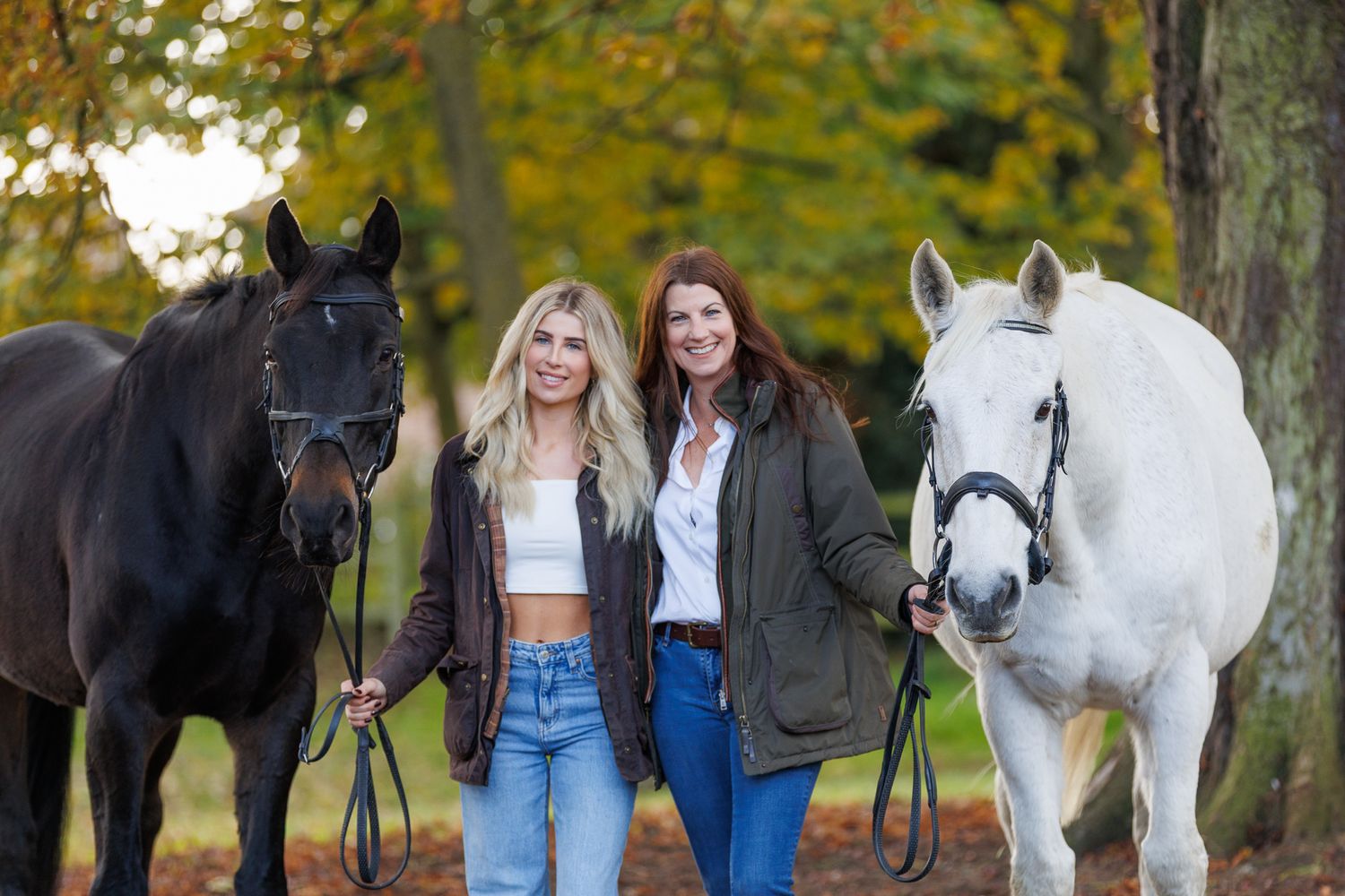 A beautiful black and white paint horse stands with a person on a sunny autumn day outdoors.