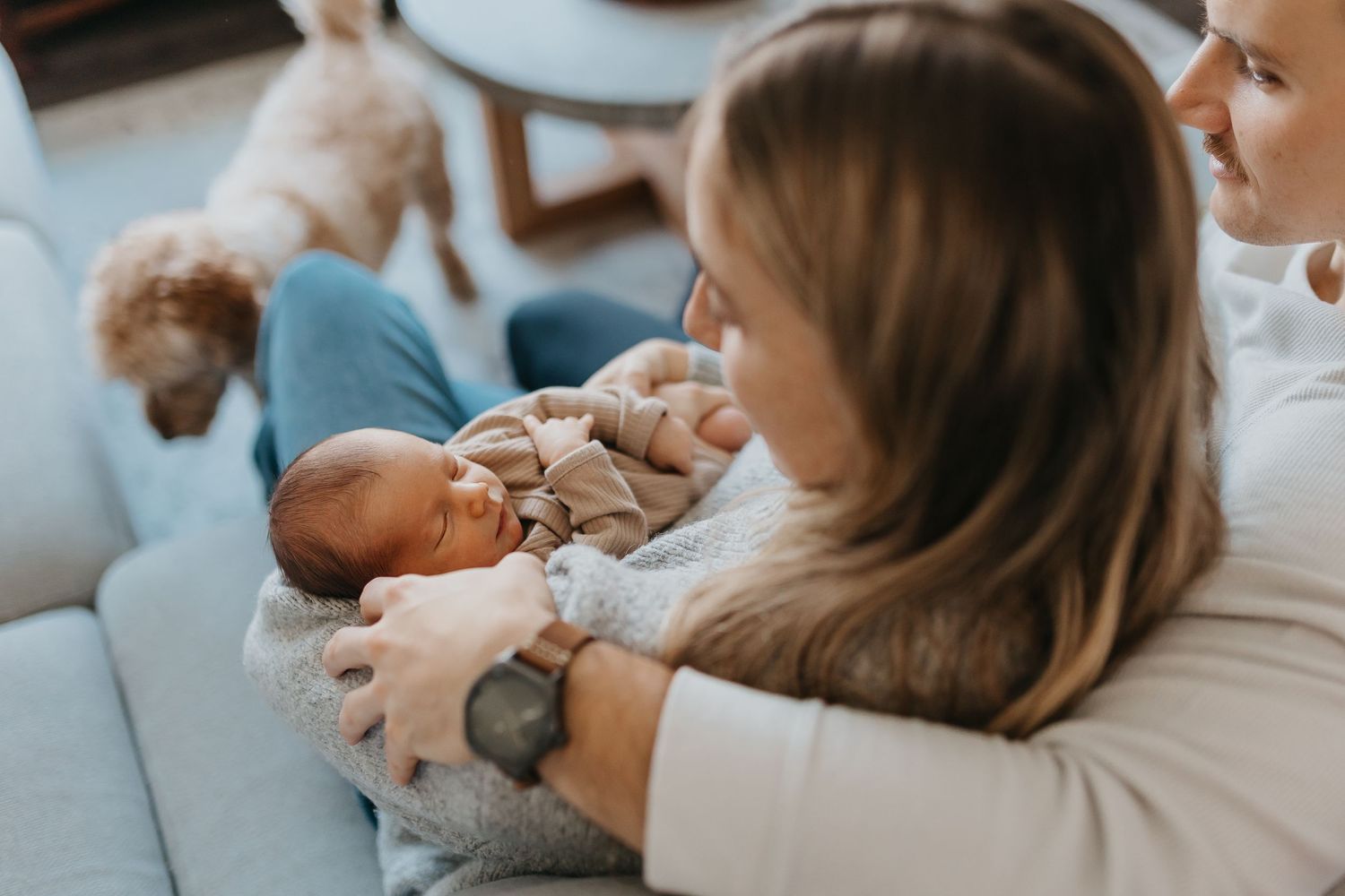 Parent and baby lying together on white bedding while bonding during an intimate lifestyle photography session.
