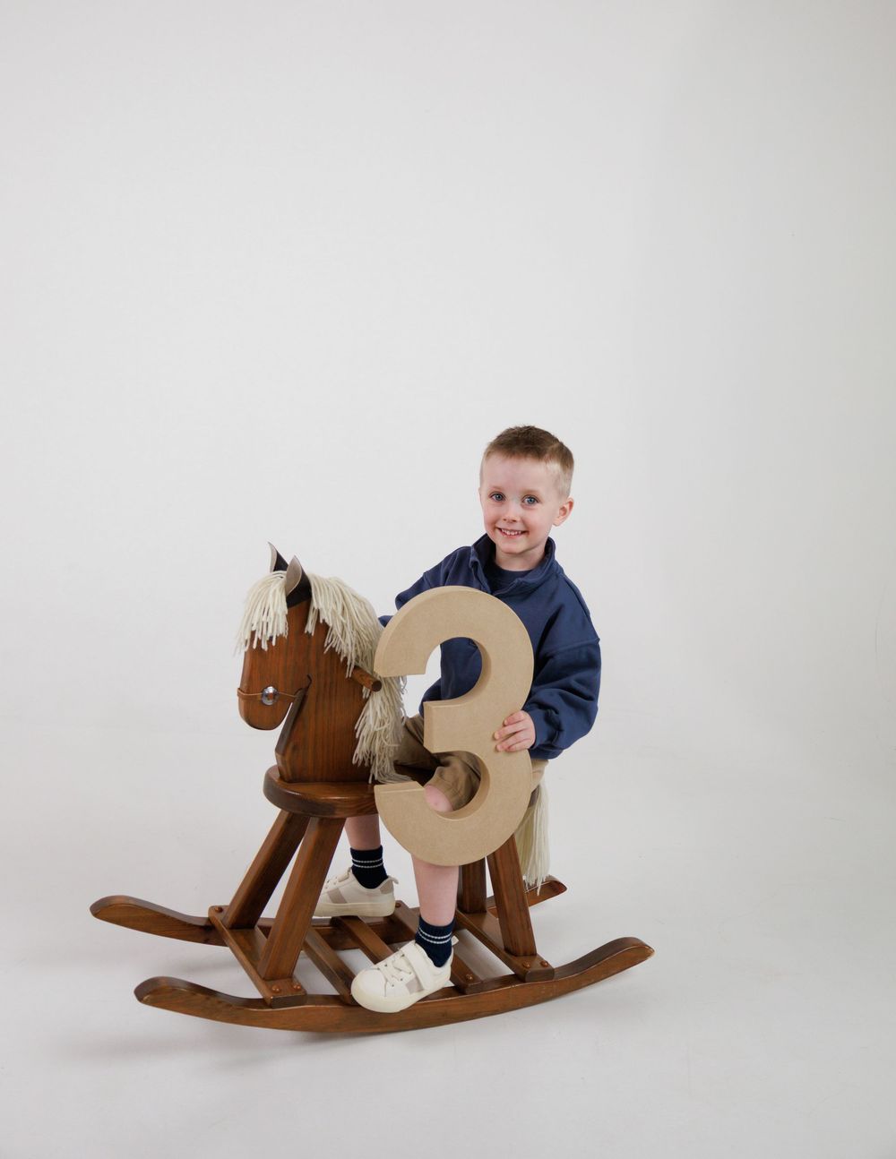 A series of photos showing a child playing on a wooden rocking horse against a white background.