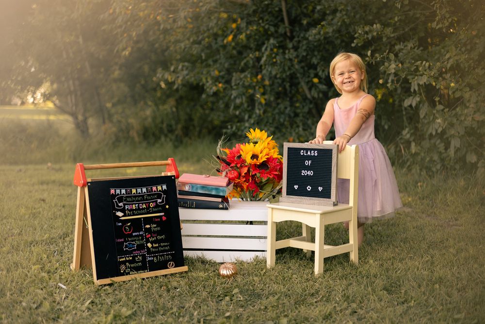 A rustic outdoor scene with a chalkboard sign and floral decorations arranged on wooden furniture in a garden setting.