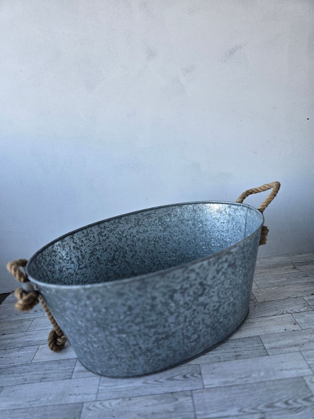 Rustic oval galvanized metal tub with rope handles, perfect for storage, planting, or beverage cooling.