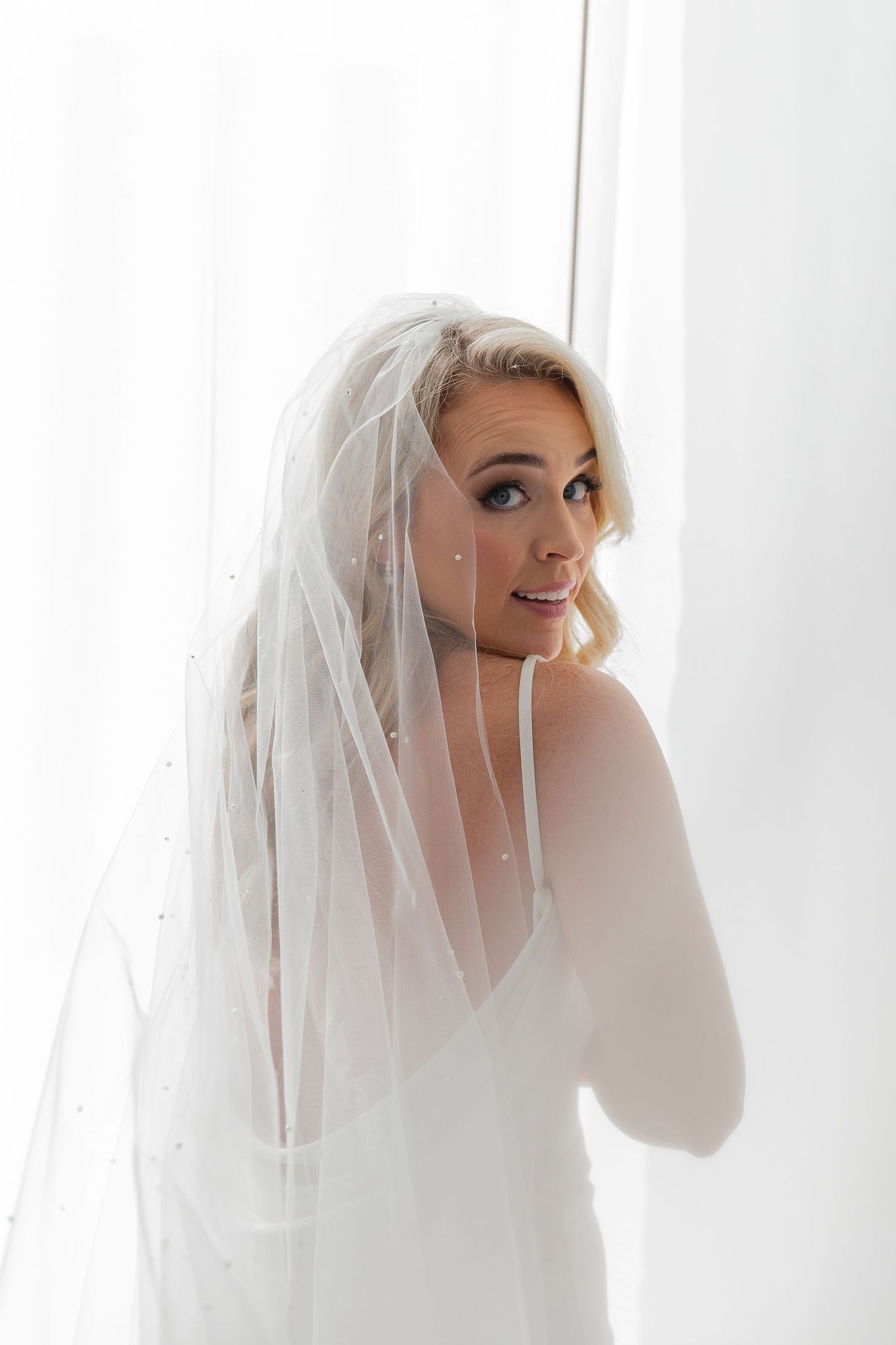 A bride wearing a white veil poses against a bright window in a series of candid shots. NASHVILLE WEDDING PHOTOGRAPHER