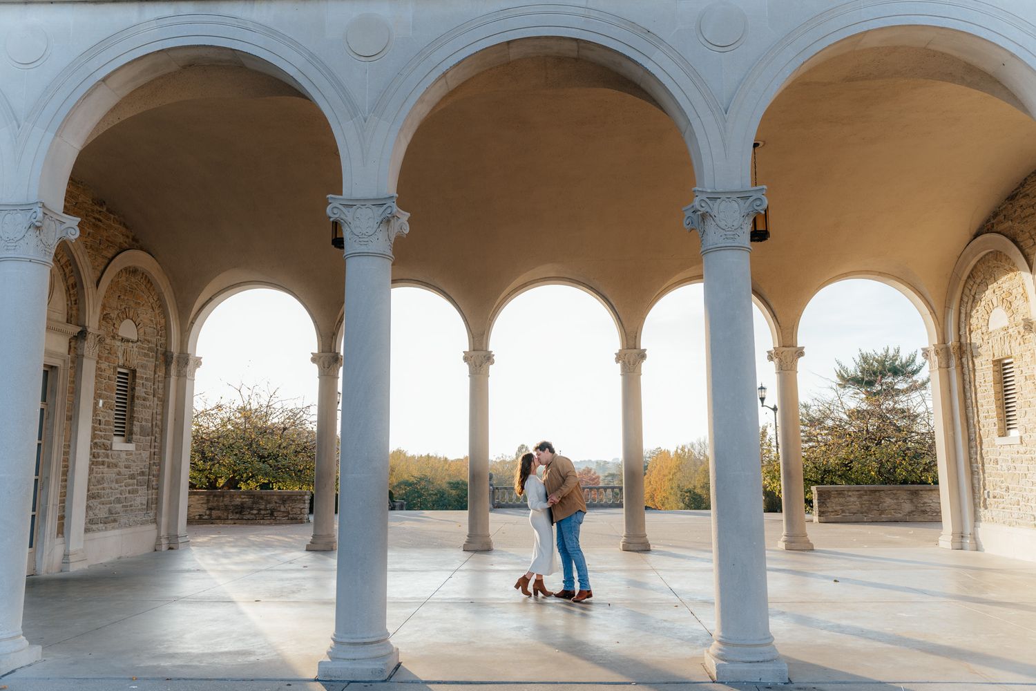 A romantic moment under ornate stone arches at sunset.