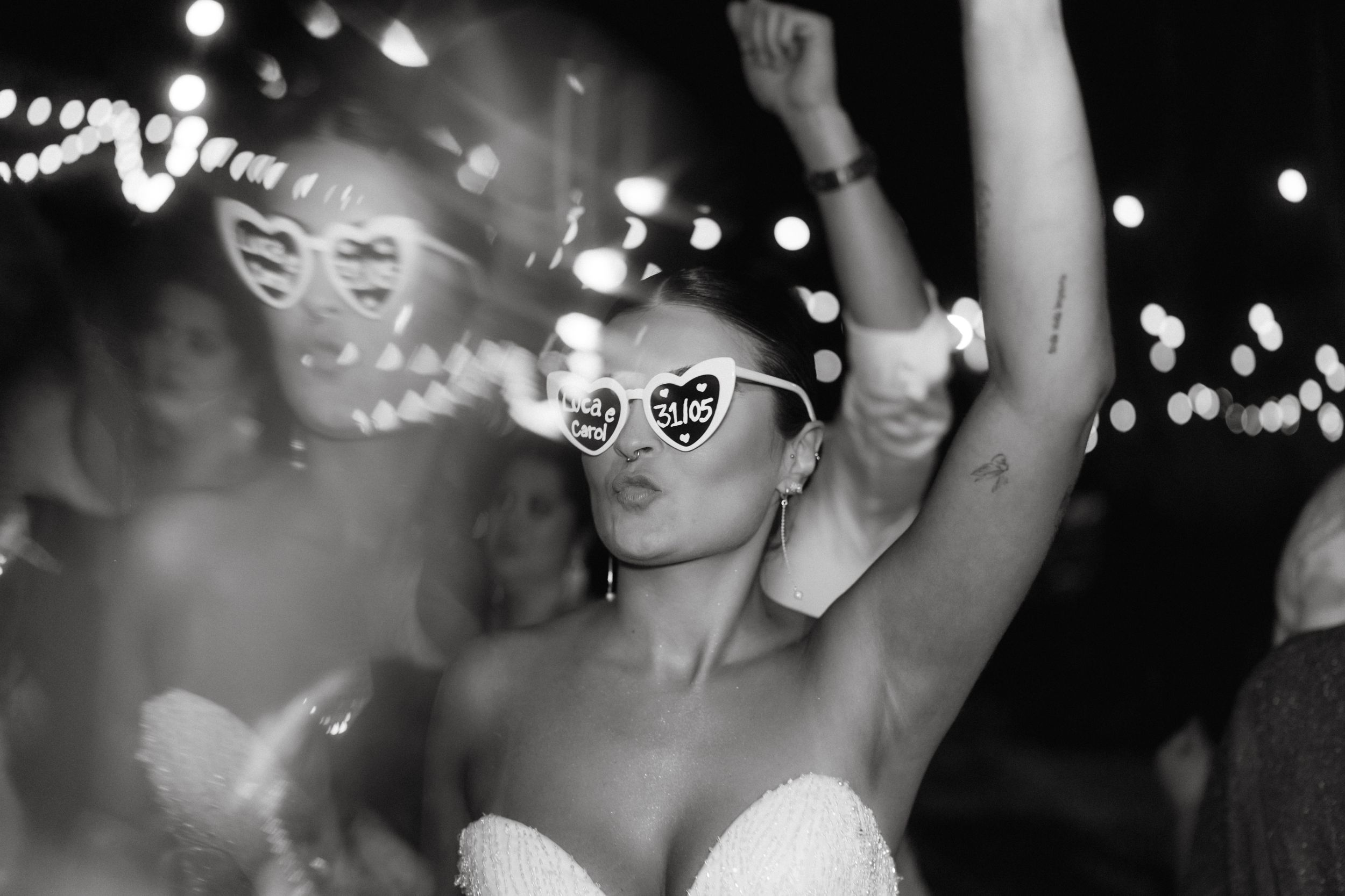 Wedding celebration with party goers dancing under string lights at night.