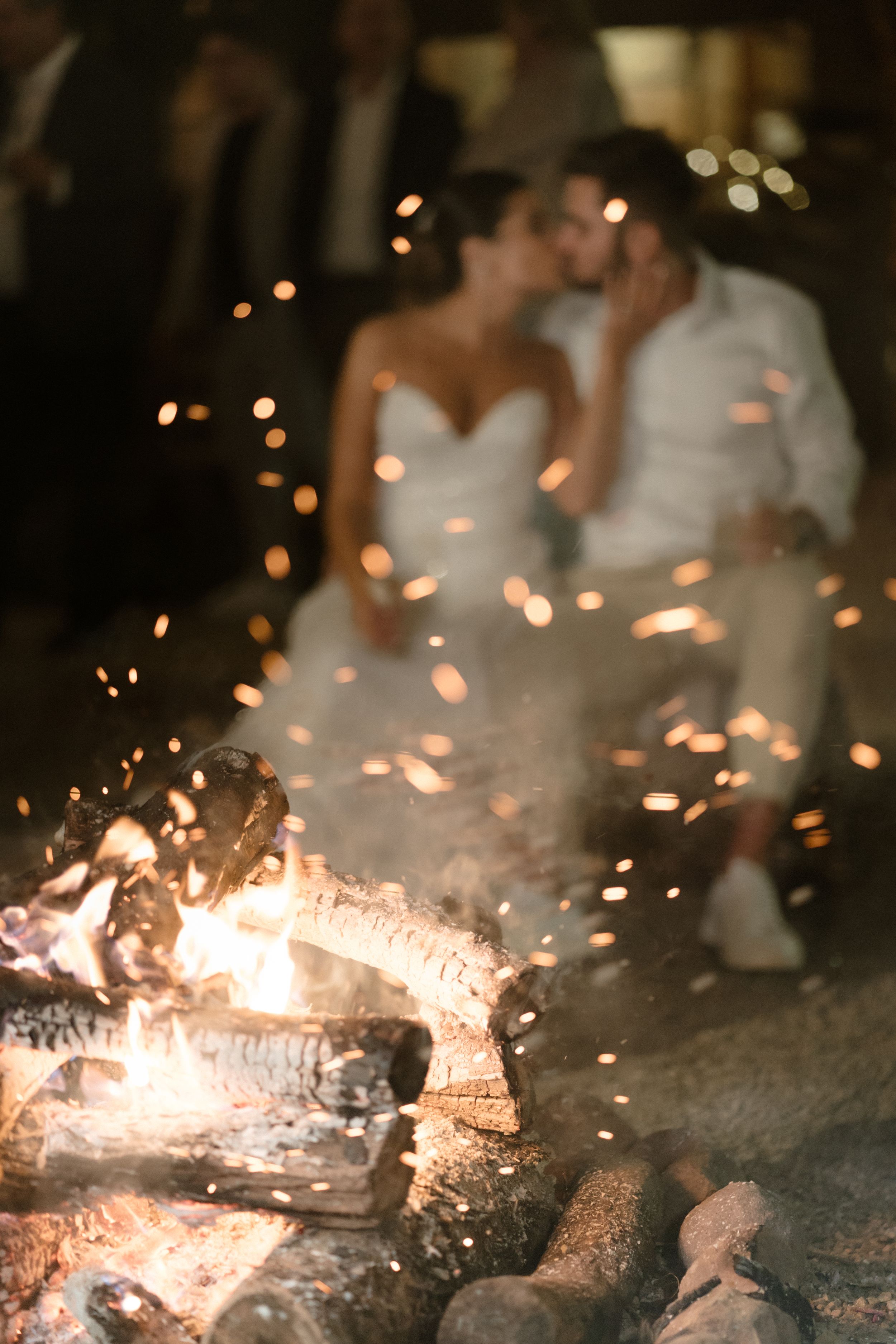 A romantic wedding scene with sparklers and a bonfire creating magical lighting effects.