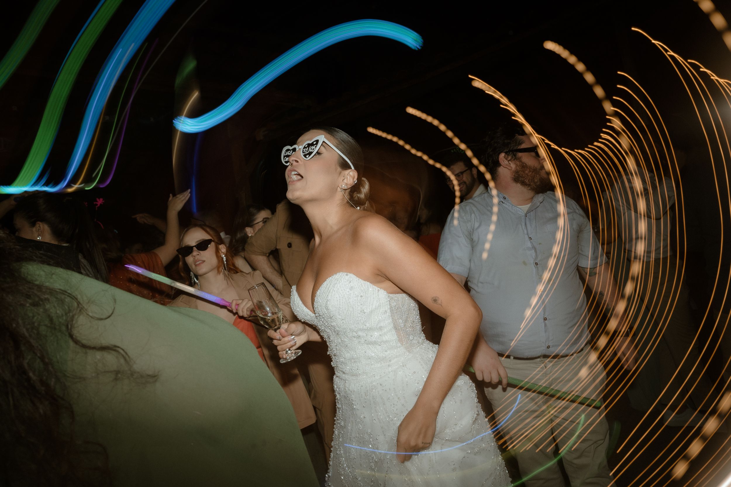 White-gowned dancer twirls on dance floor with light trails creating dramatic motion blur effect.