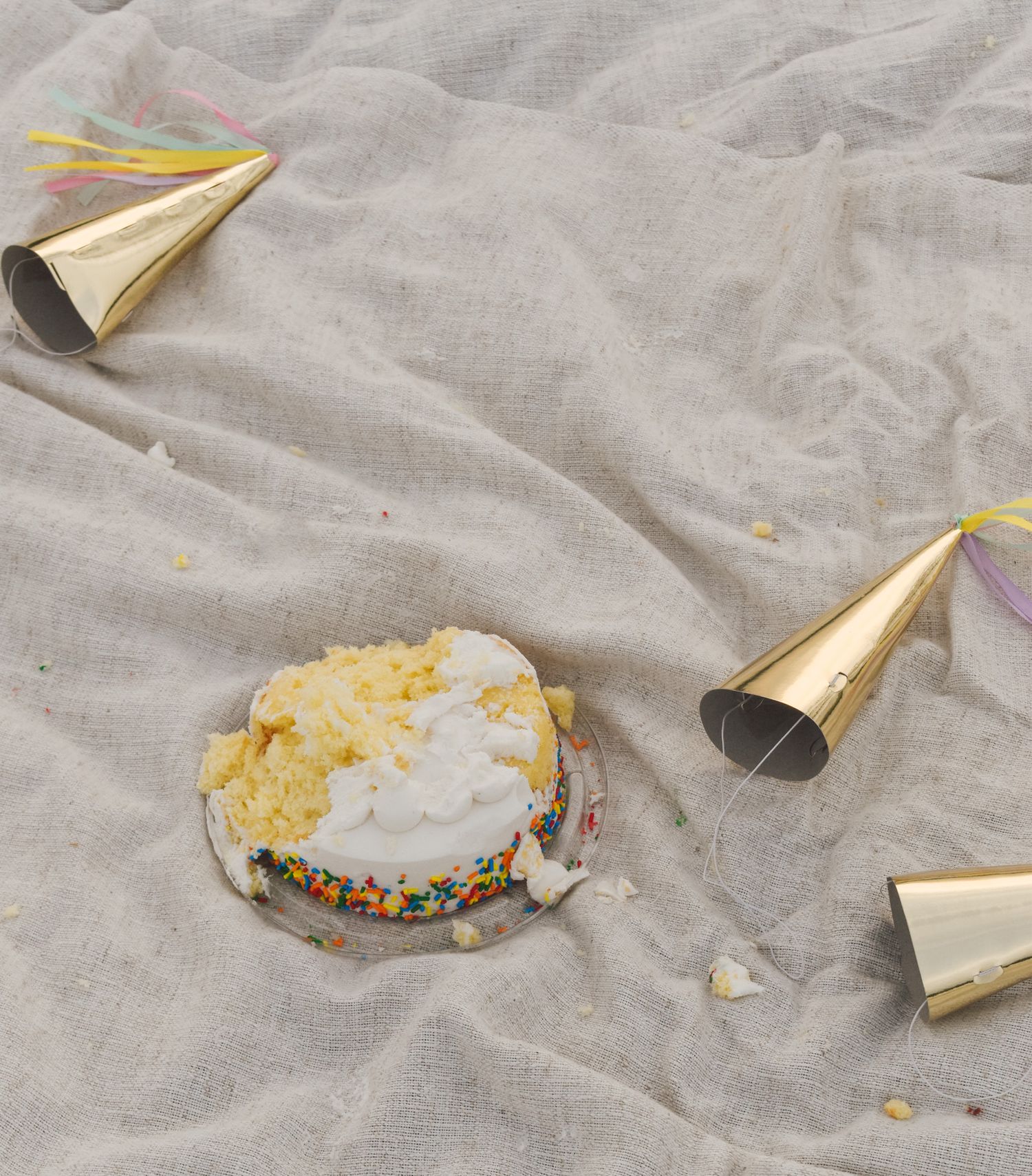Party favor horns and confetti scattered on wrinkled gray fabric.