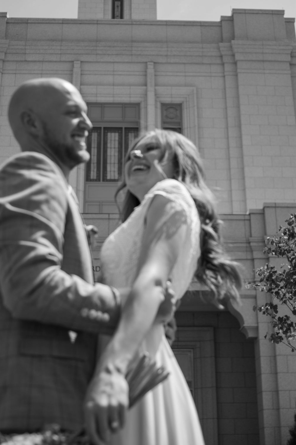 Bride and groom laugh together in front of Rexburg temple.