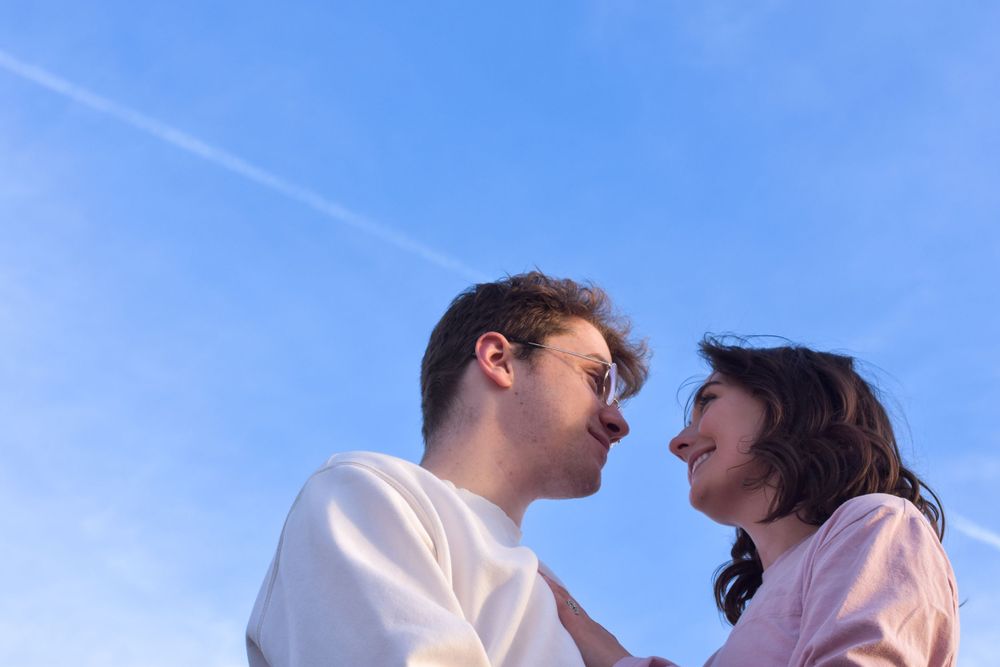 Couple smiles at each other as plan flies over head in Provo, Utah.