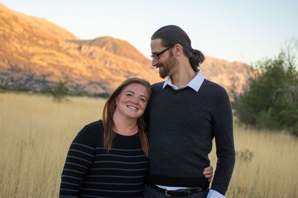 Married couple smiling in Utah landscape. He smiles at her.