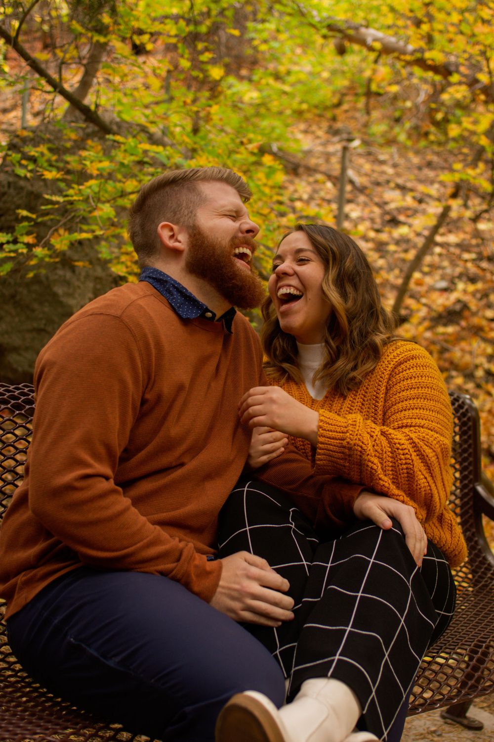 Couple laughs together in an autumn forest in Utah.