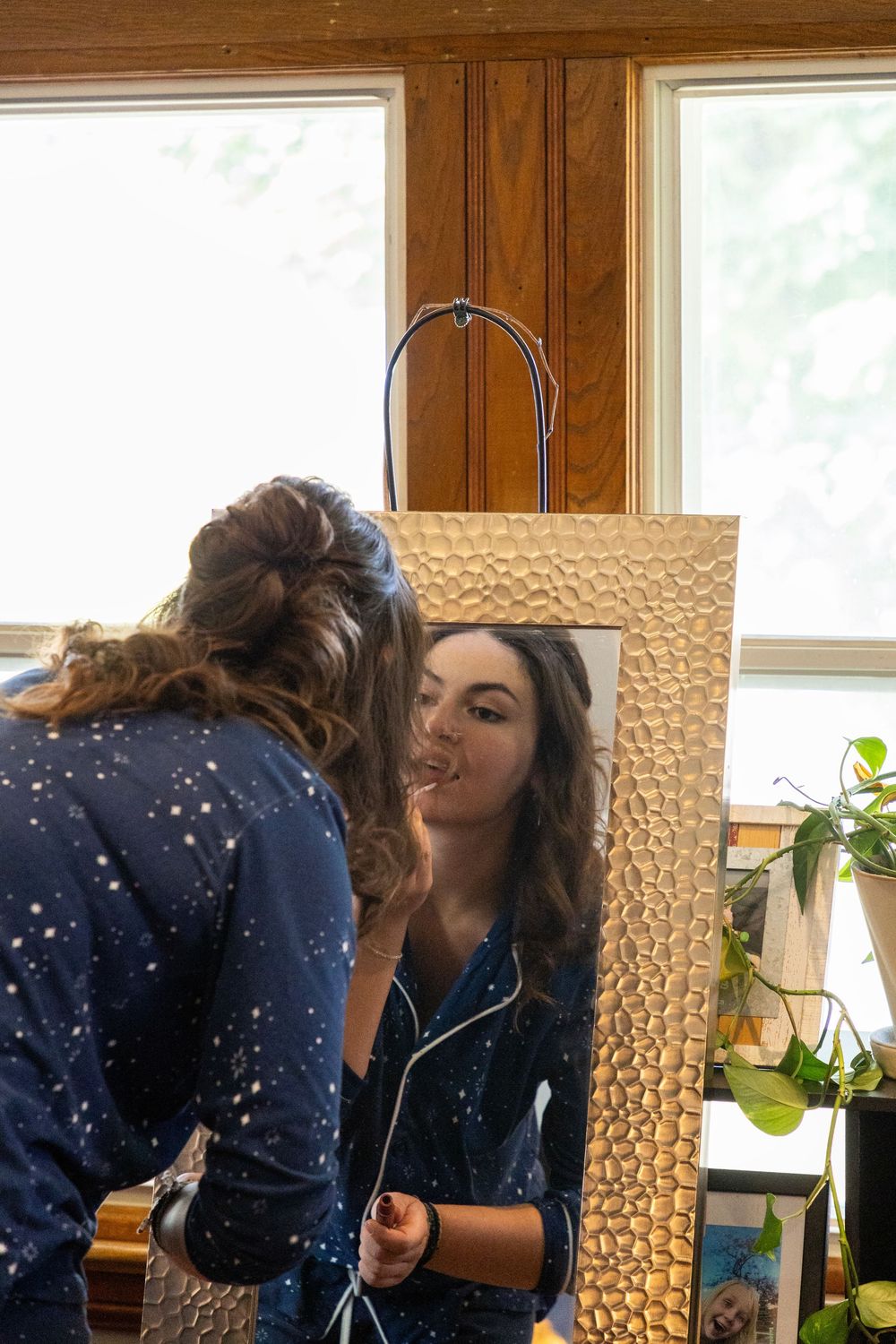 a bridesmaid putting on makeup in a mirror