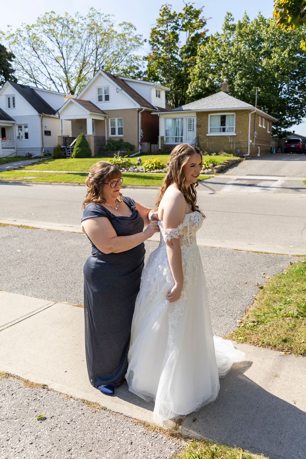 mother and daughter outside fixing brides dress