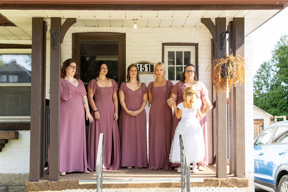 bridesmaids reacting on a porch along with the flower girl