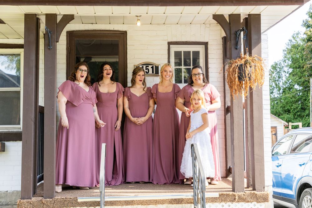 bridesmaids reacting on a porch along with the flower girl