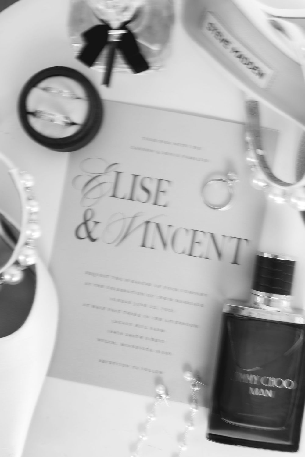 Wedding invitation cards with elegant typography and Jimmy Choo perfume bottle in a luxurious flat lay arrangement.