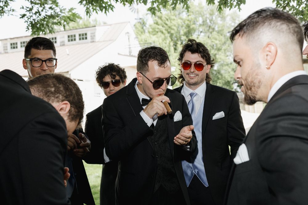 A group of well-dressed men in dark suits laughing and socializing at an outdoor event.