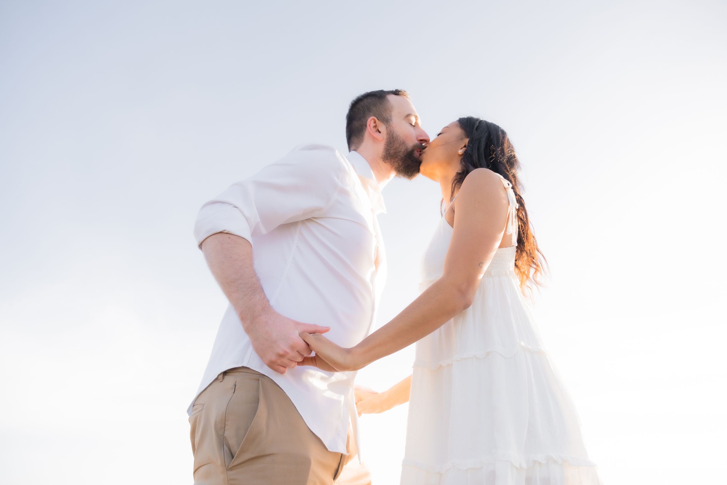 engaged couple kissing, holding hands.