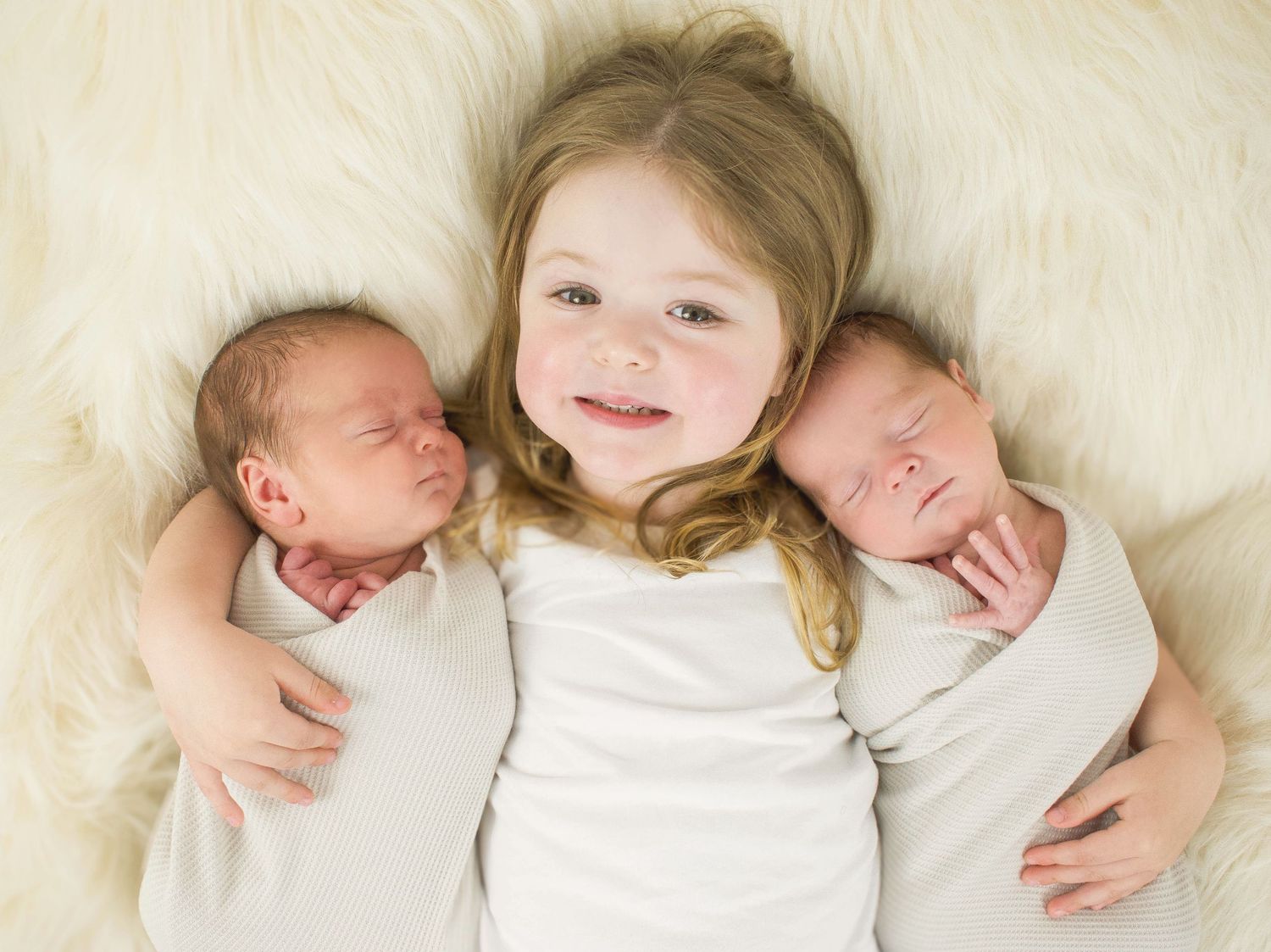 Sweet newborn photography on white fur backdrop showing tender moments.