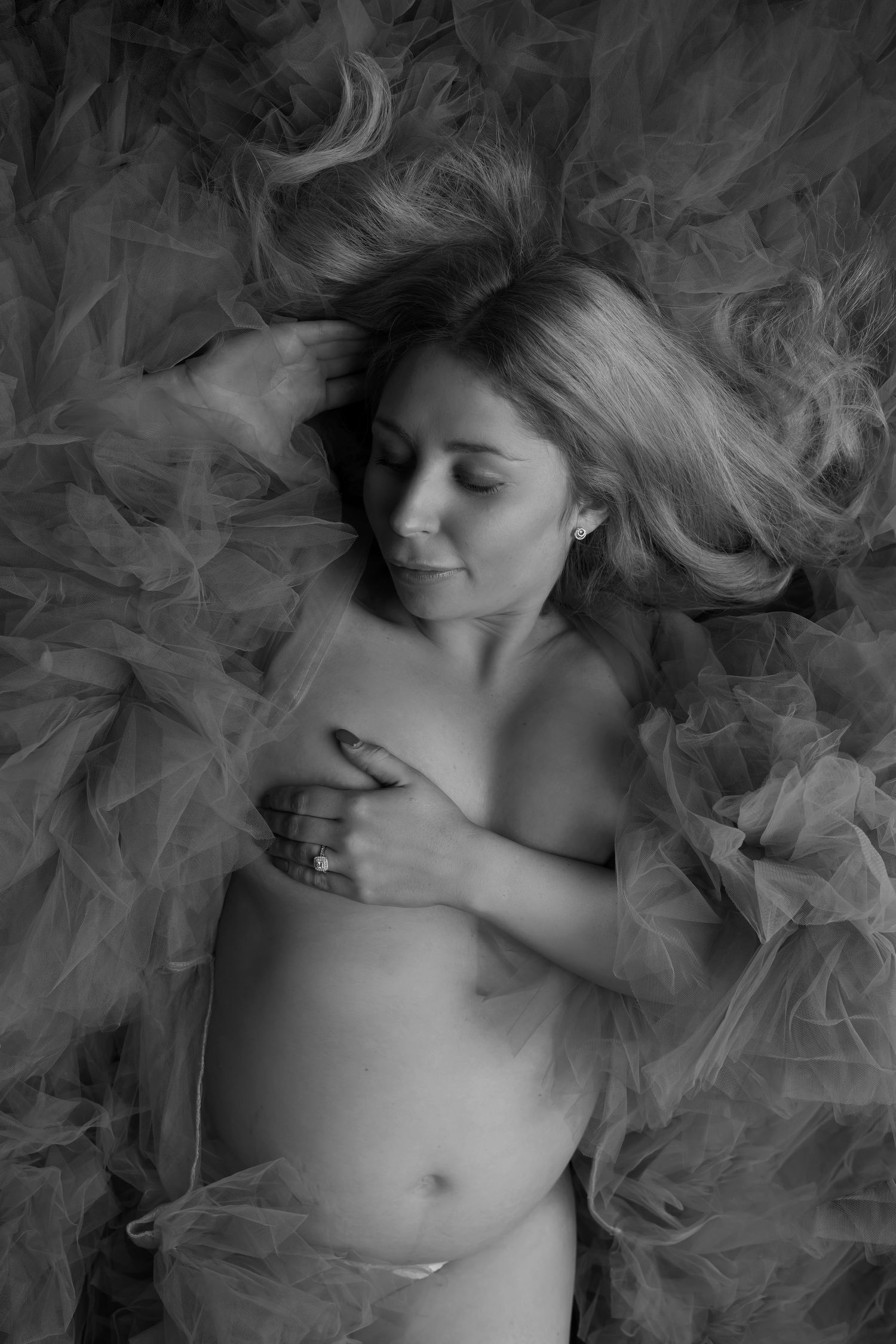 Dreamy black and white maternity portrait with flowing tulle fabric.