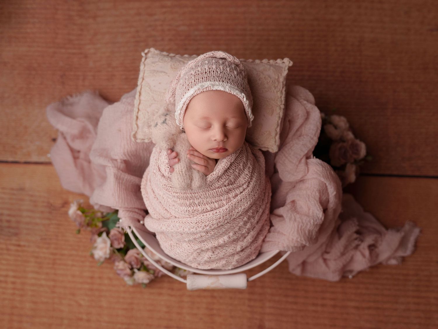 Six connected newborn photography images with soft pink tones and wooden backdrop showing sleeping baby in different poses.