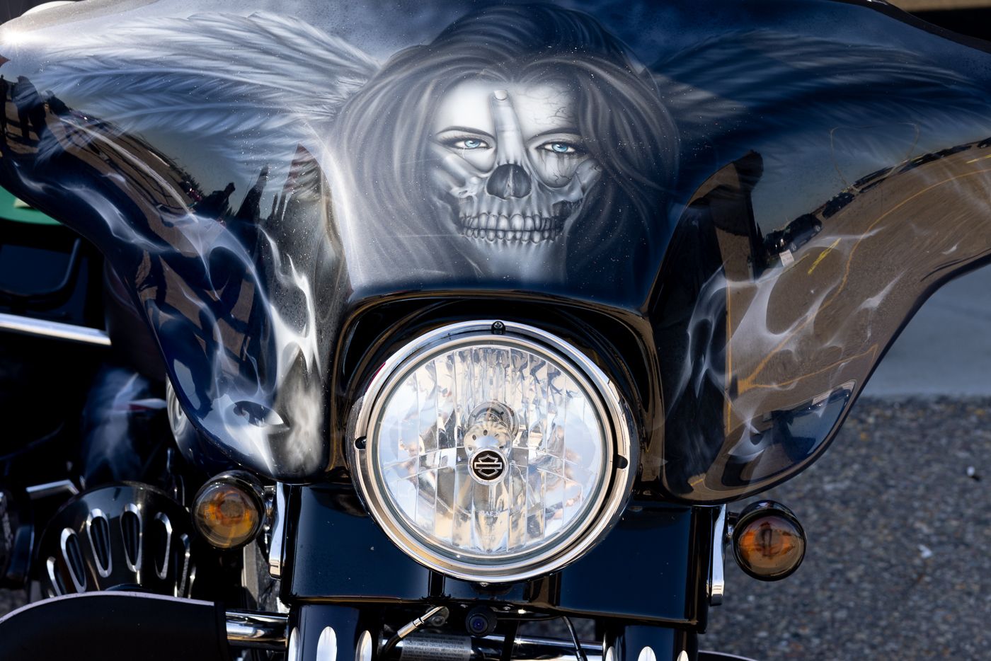 Clean polished custom cruiser motorcycle headlamp with chrome trim reflects light during daytime parking.