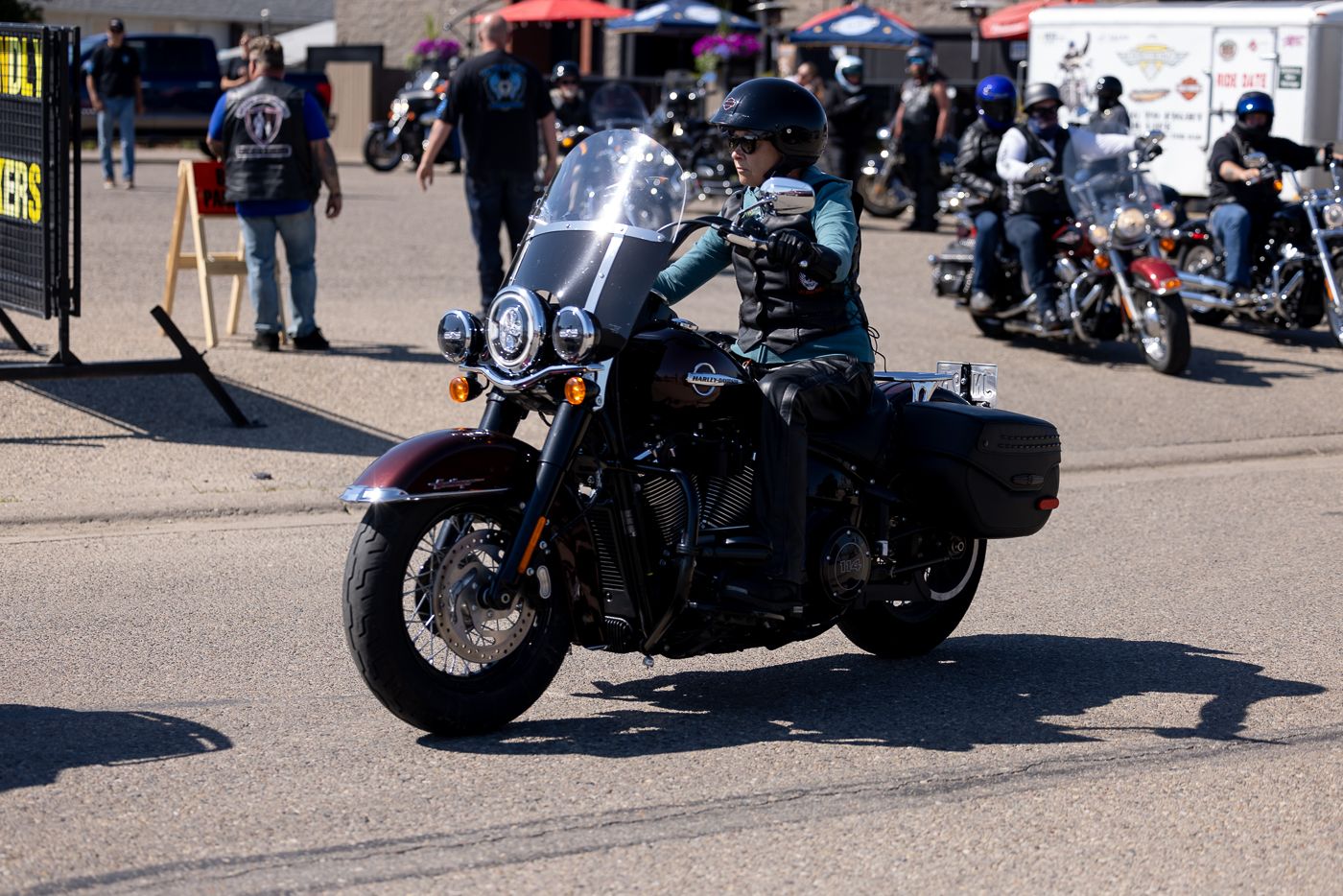 Black cruiser motorcycle with saddlebags parked at outdoor motorcycle event with other bikes in background.