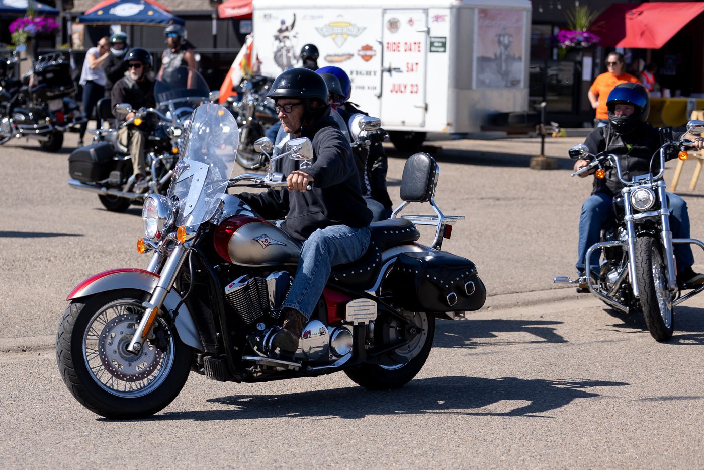 Custom motorcycles and bikes lined up at an outdoor motorcycle show under blue umbrellas and tents during daytime.