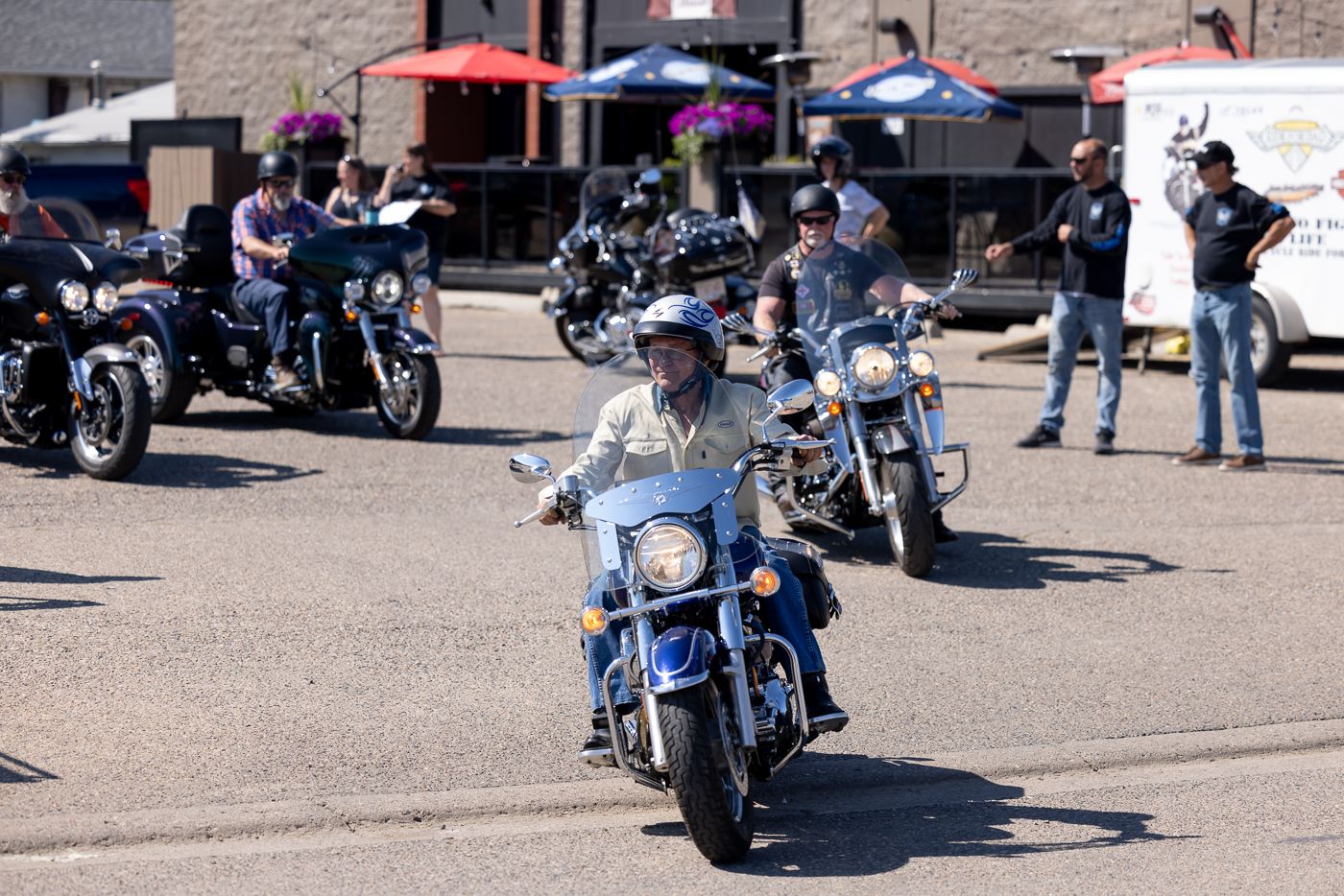 Motorcycles parked in a sunny outdoor lot with riders gathering for a motorcycle event.