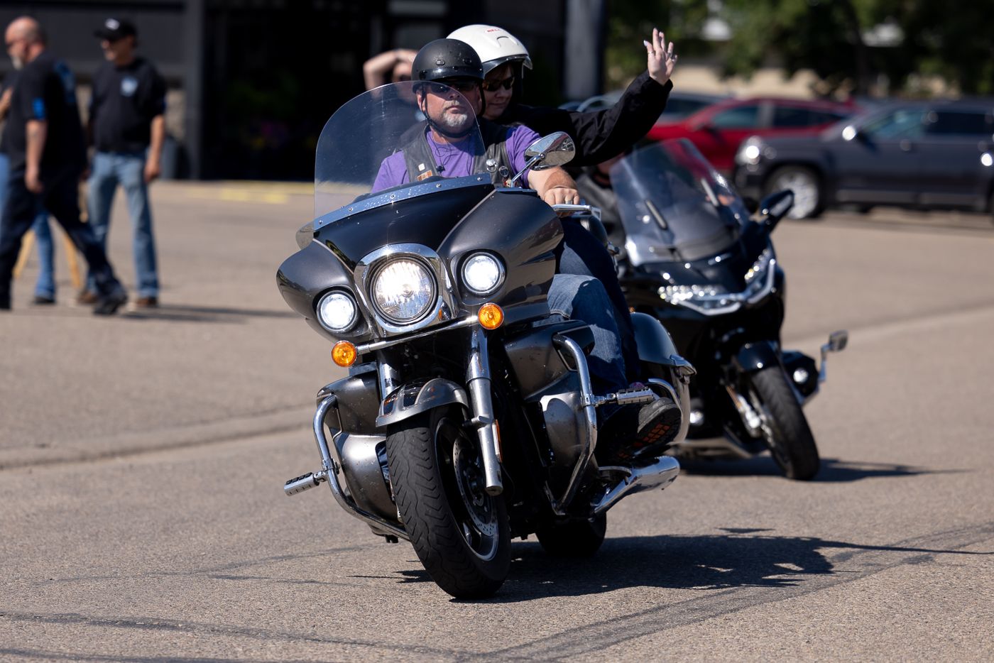 A line of parked black motorcycles at an outdoor gathering on a sunny day.