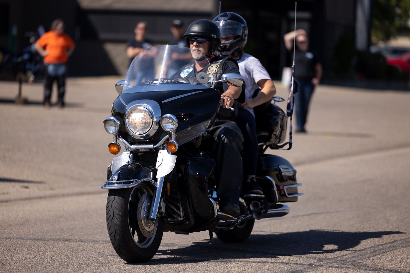 Multiple black motorcycles parked in formation at an outdoor motorcycle event on a sunny day.