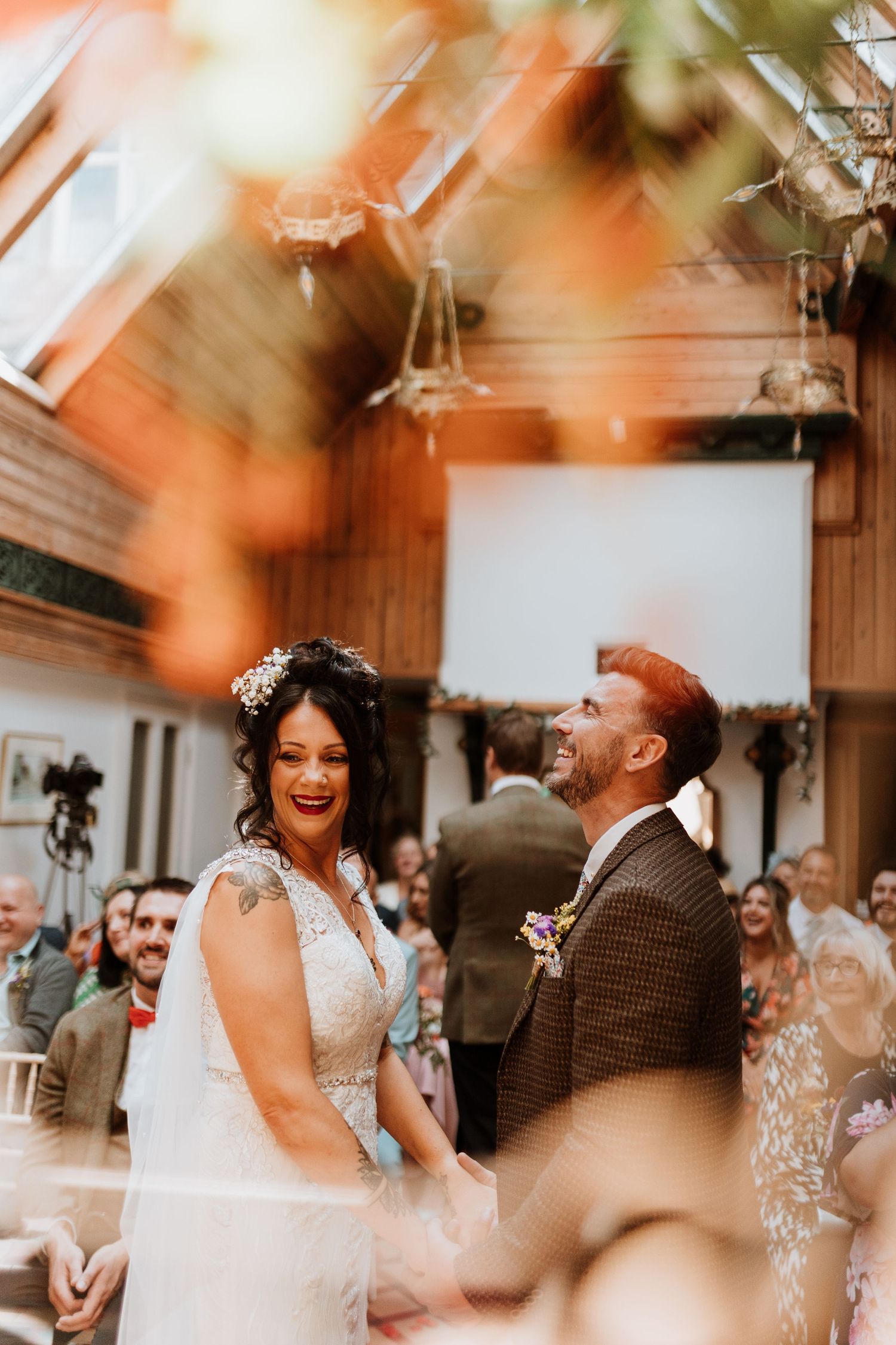 A wedding ceremony scene with elegant place settings, flowers, and a warm chandelier glow overhead.