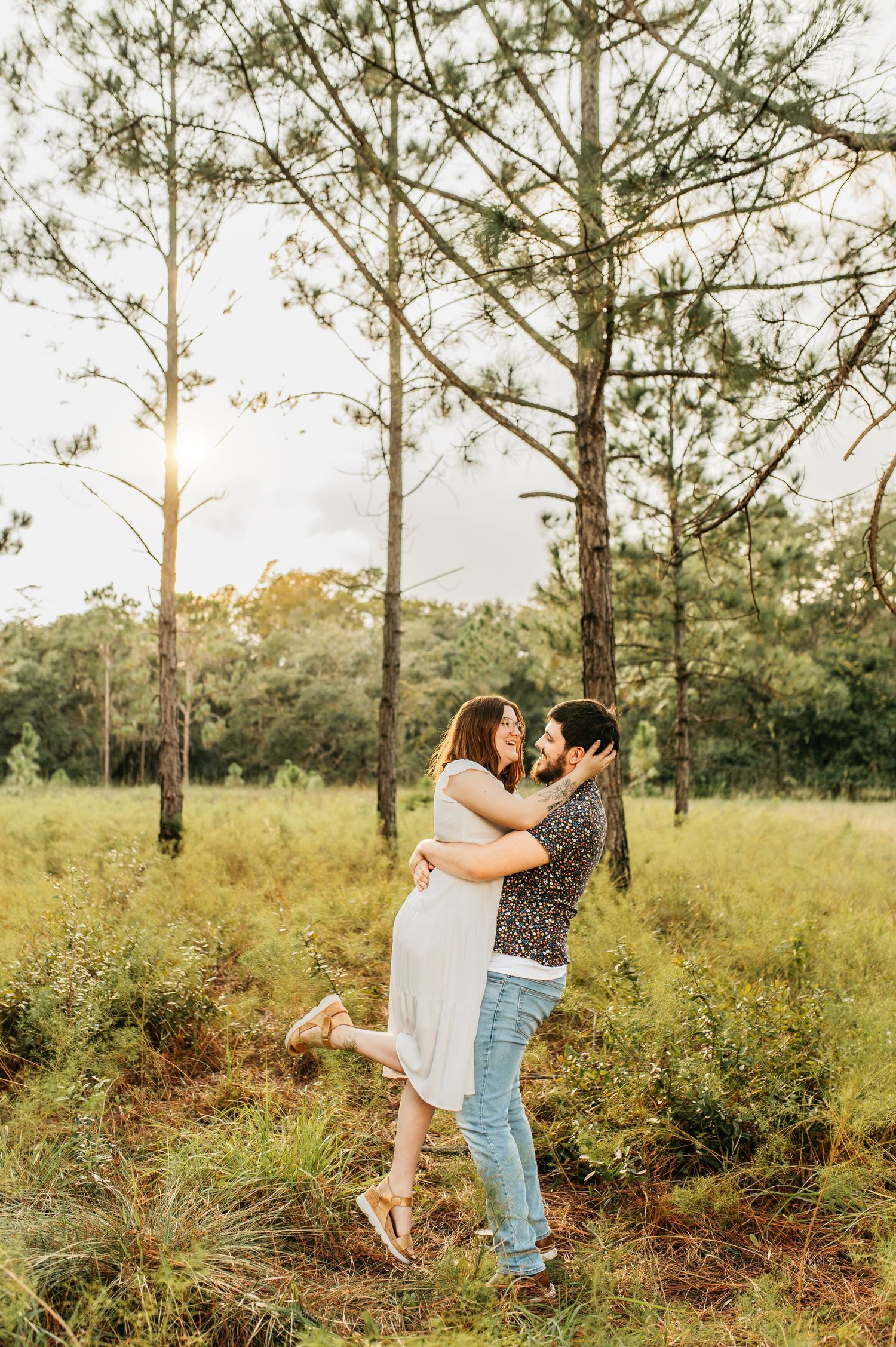 A joyful couple embracing in a sunlit pine forest.