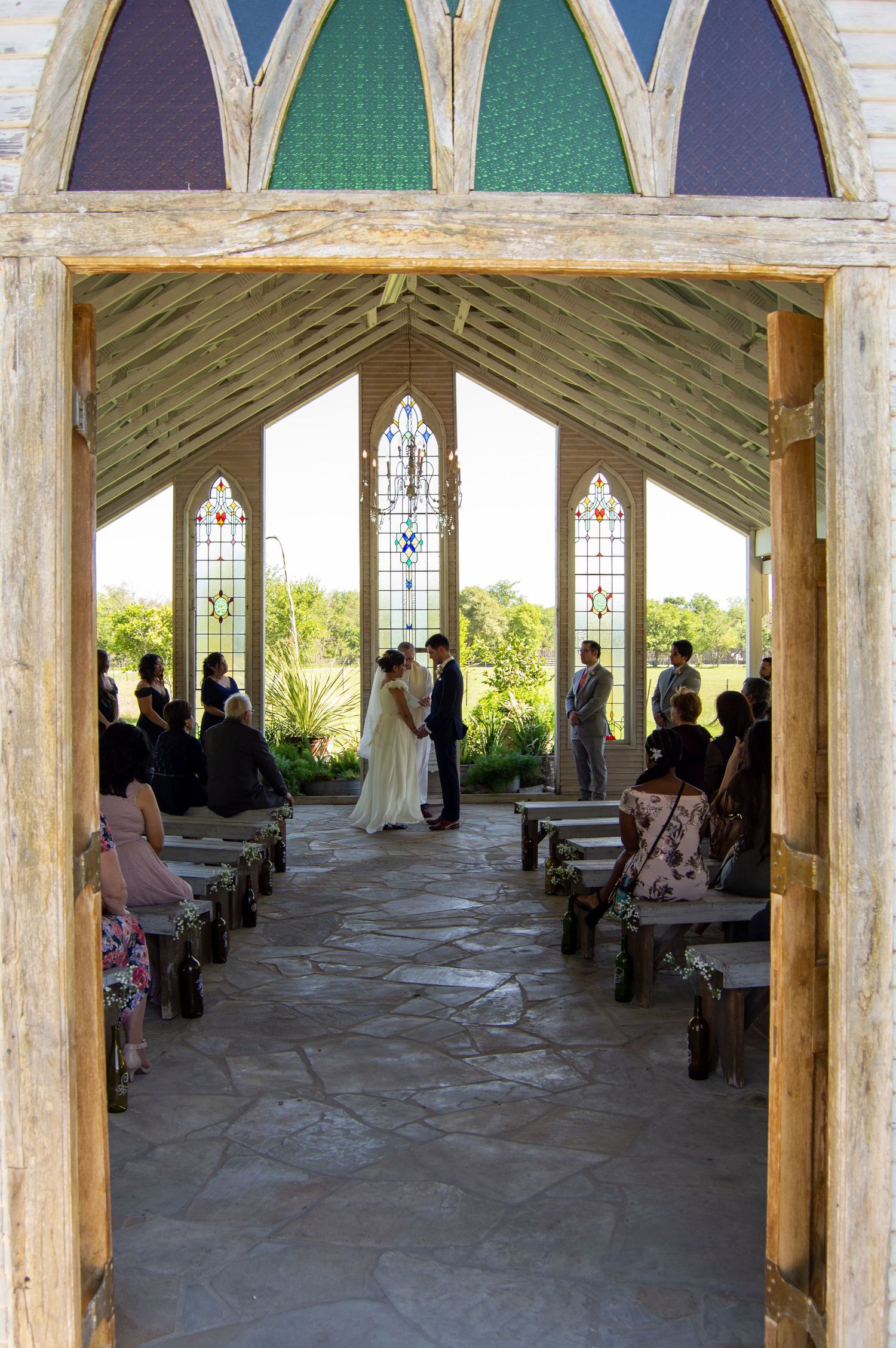 Interior panorama of rustic chapel with painted arches and stained glass windows.