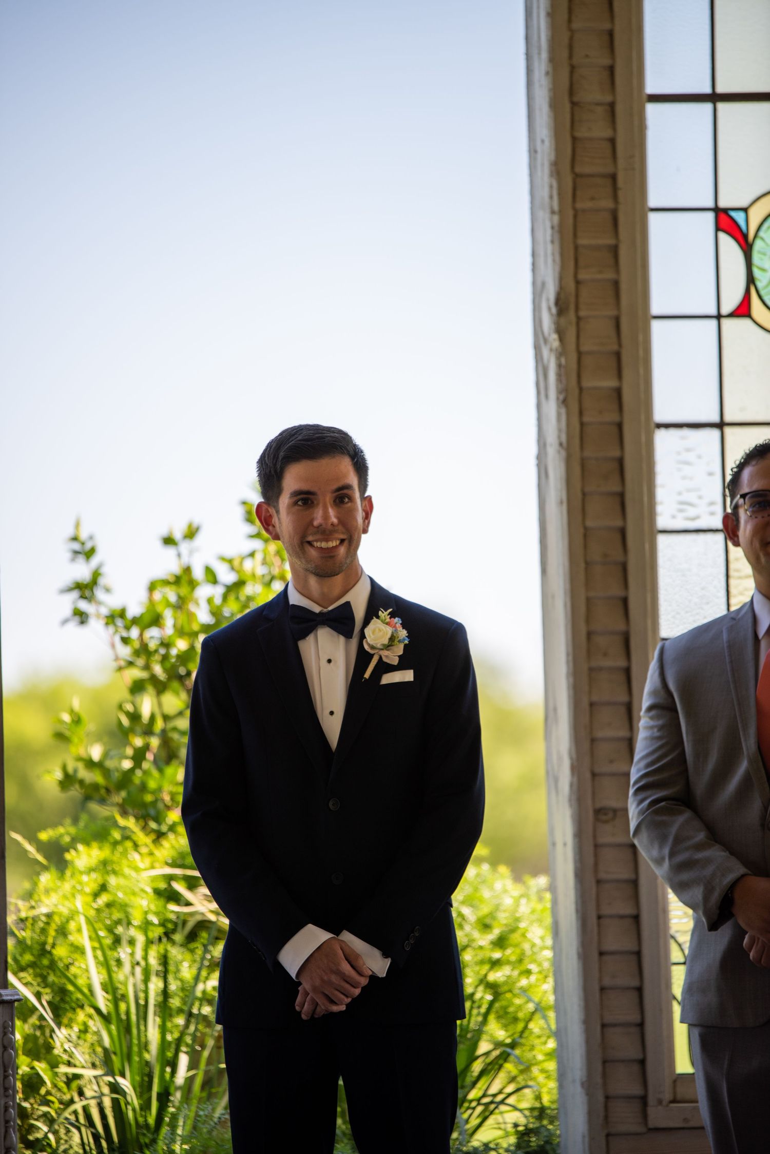 Wedding party members standing under chapel archways with natural lighting.