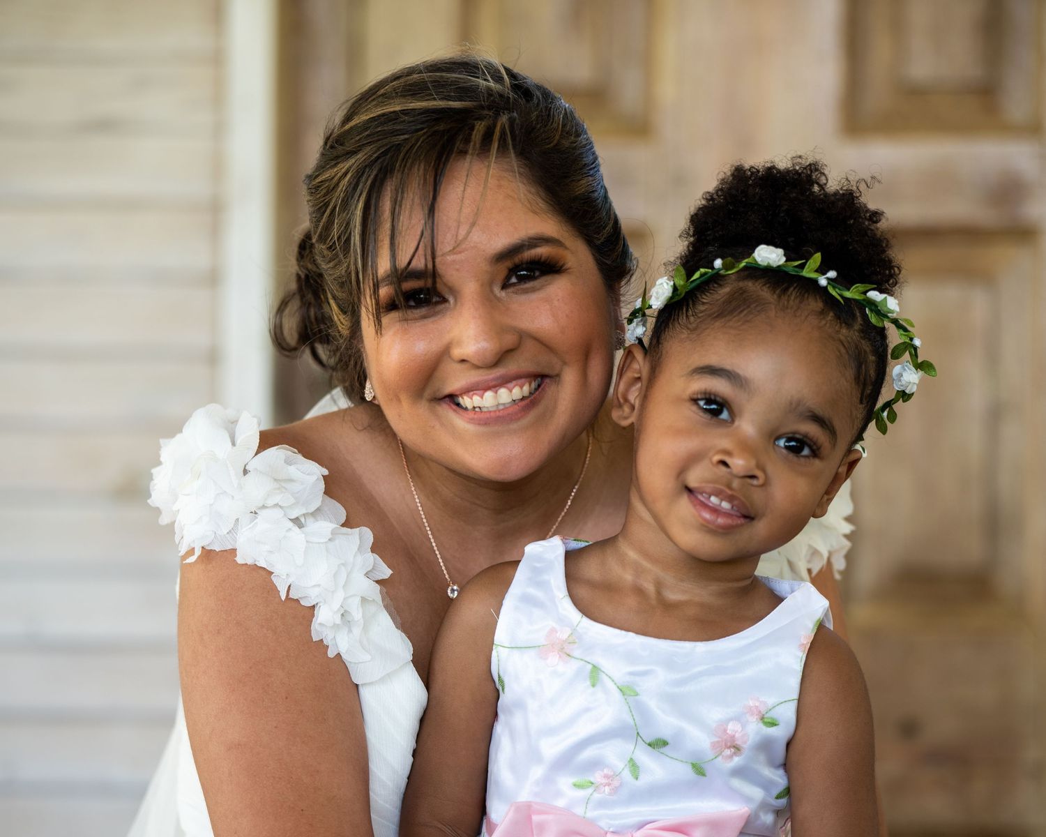 Wedding portraits showing loving interactions against white building backdrop.