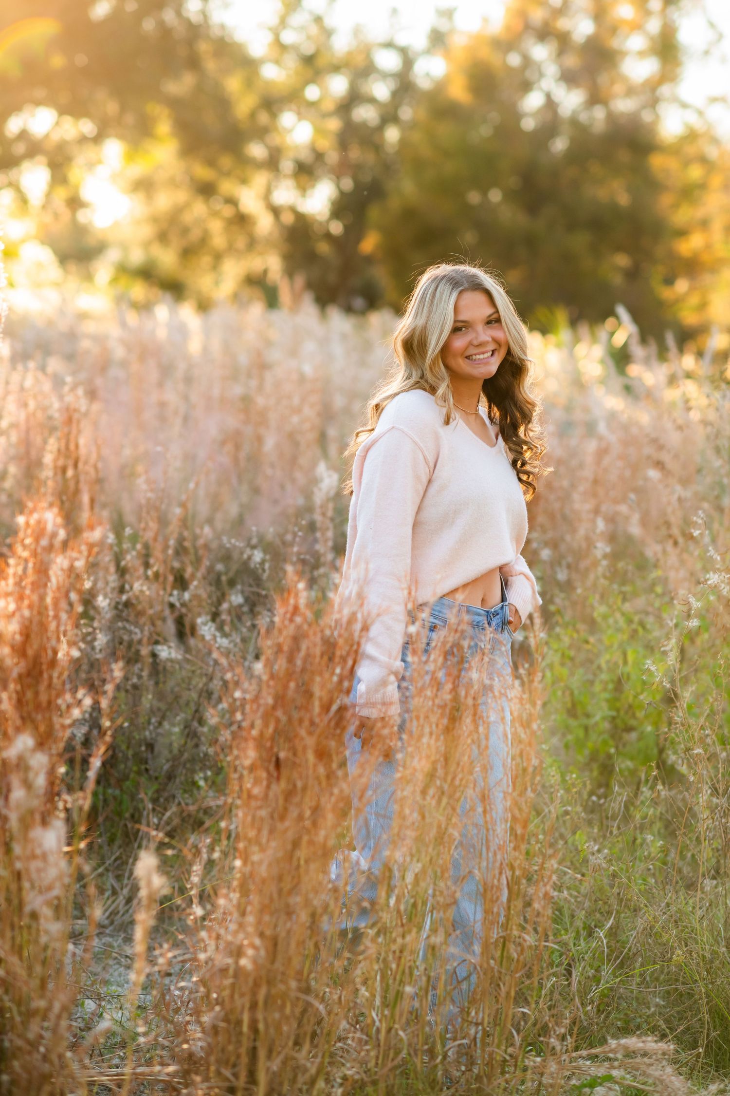 Natural outdoor photography in a field of tall grass and wildflowers during golden hour sunset lighting.