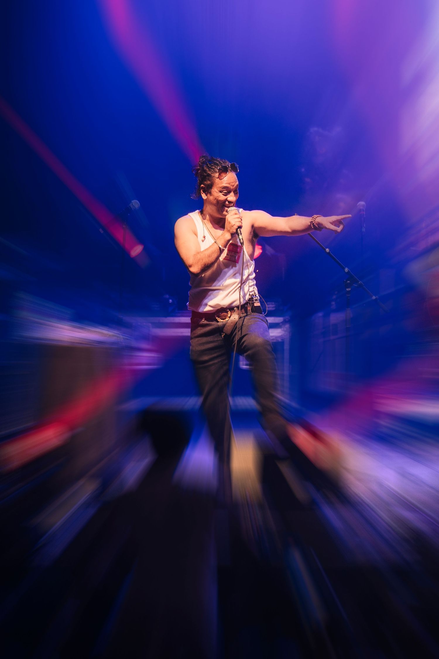 Dynamic concert performance photo with dramatic purple lighting and motion blur effects on stage.