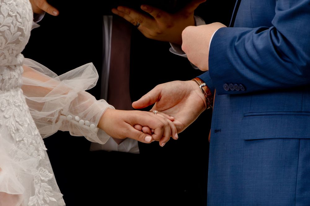 Close-up of hands exchanging rings during an intimate wedding ceremony.