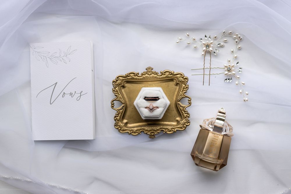 Wedding details in white and gold featuring vows card and decorative ring holder.