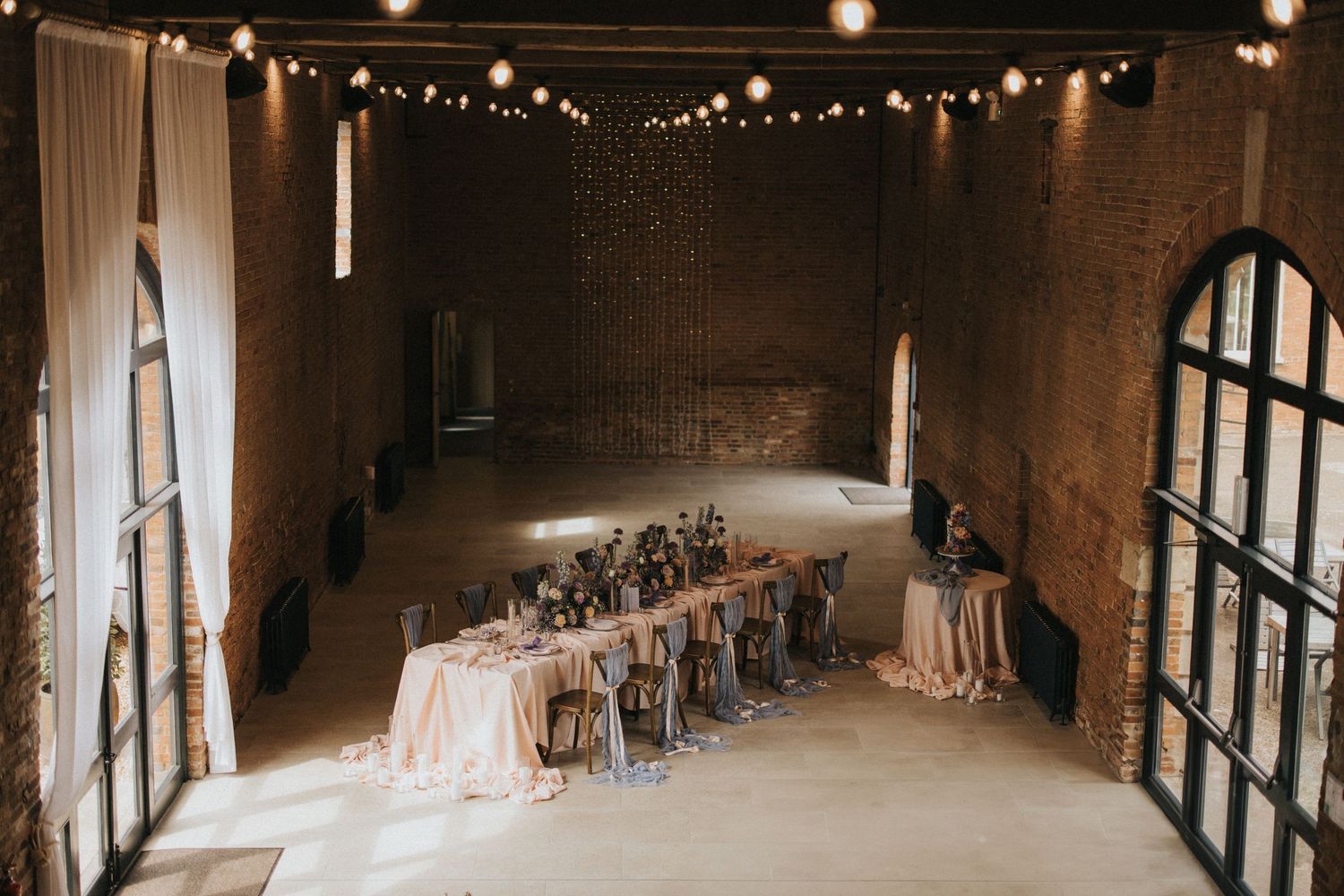 Rustic wedding reception with string light and long banquet tables draped in blush linens at Elsham Hall - captured by Grimsby photographers