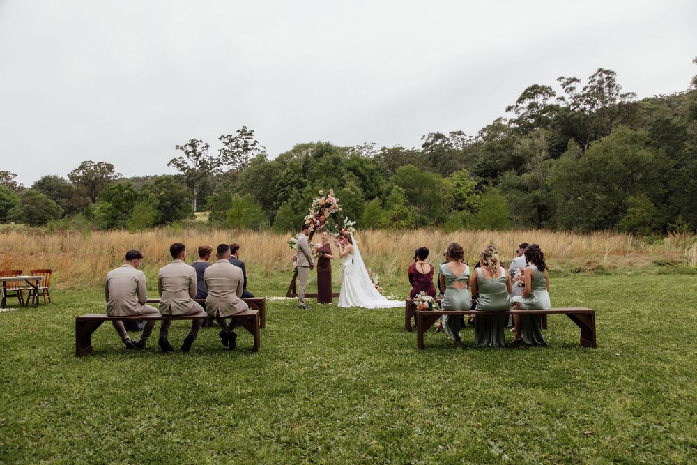 A series of photos showing people sitting in a line on a grassy field, creating a playful optical illusion sequence.